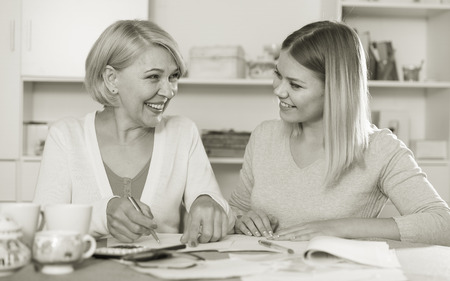 Maintaining home accounting. Daughter and her elderly mother are watching documentsの写真素材