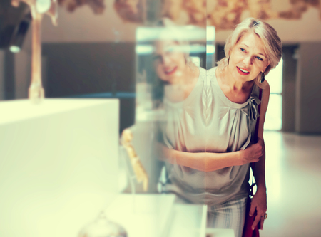 Positive woman visitor in the historical museum looking at exhibit  の写真素材