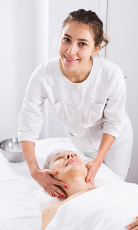 Mature woman client having face massage procedure in beauty salonの写真素材
