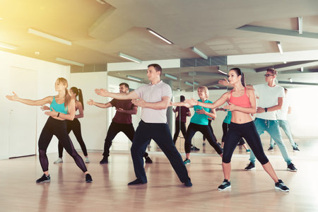Happy different ages adults training swing steps at dance class