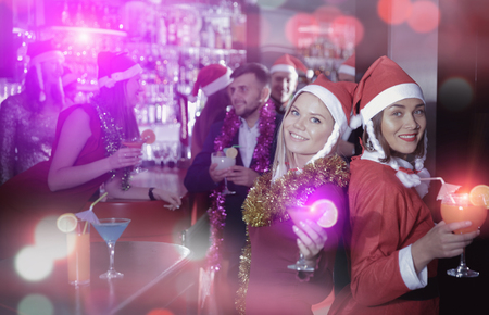 Two young women with cocktails having fun on new year party at nightclubの写真素材