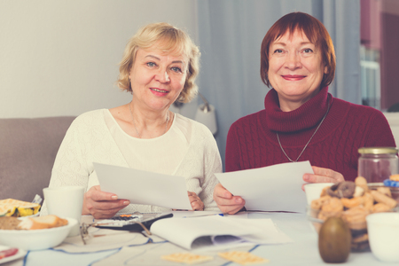 Portrait of cheerful mature females with documents communal paymentsの写真素材