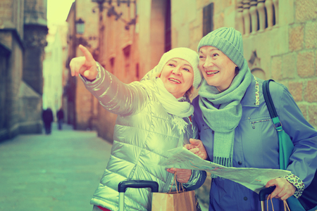 Senior woman with female friend traveling together looking for destination with city map
の写真素材