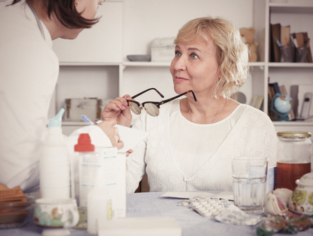 Portrait of a mature woman and a doctor at a table with medicinesの写真素材