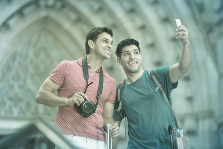 Men are walking with suitcases and making selfie near sights in Barcelonaの写真素材