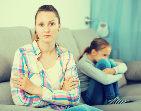 Young sad mother quarreled with schoolgirl daughter at homeの写真素材