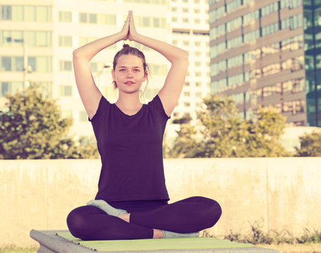 Girl making yoga meditation in lotus pose on urban landscape backgroundの写真素材