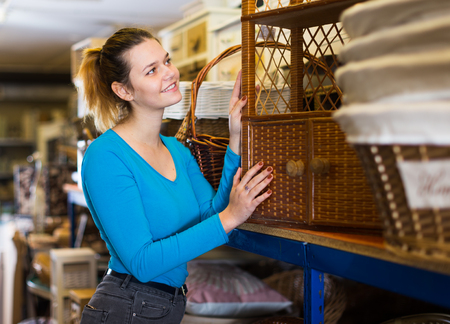 Teenager female choosing wicker ambry in decoration and furniture store の写真素材