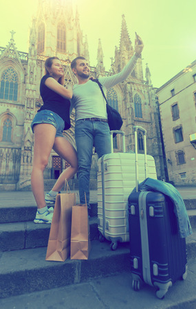 
 young tourists with travel bags makes selfie on the streetの写真素材