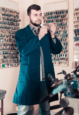 Smiling male worker shaping new key in repair workshopの写真素材