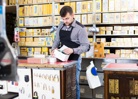 Young seller checking boxes with door details in houseware store