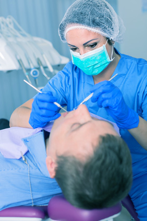 dentist professional filling teeth for man patient sitting in medical chairの写真素材