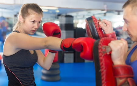 Adult man is training with woman and punching gloves in box gym.の写真素材
