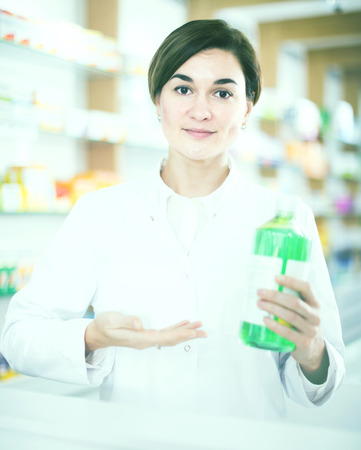Smiling european female pharmacist demonstrating assortment of pharmacyの写真素材