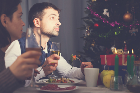 Family couple having christmas dinner with champagne and watching tvの写真素材