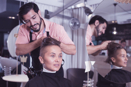 positive man hairdresser making hairstyle for woman in salonの写真素材
