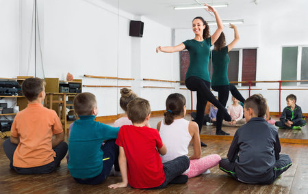 Young positive smiling  ballet dancers exercising in ballroom