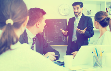 Confident businessman discussing new business project with members of his teamの写真素材