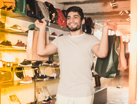 Glad adult male holding paper bags in the fashion storeの写真素材