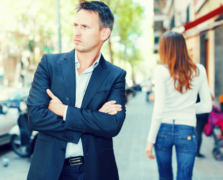 Disappointed young man in quarrel with her girlfriend backgroundの写真素材
