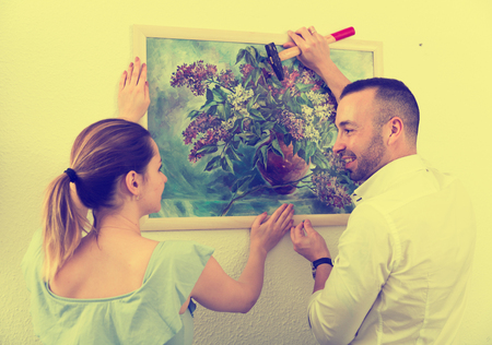 Couple is doing repair and hanging picture on the wall at home.の写真素材
