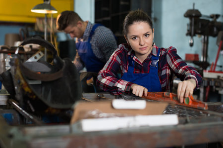 Young woman worker is working with level on her workplace in workshop.の写真素材