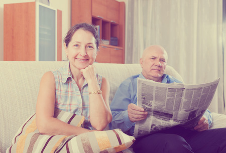 Portrait of smiling joyful family at home on the couch with the newspaperの写真素材