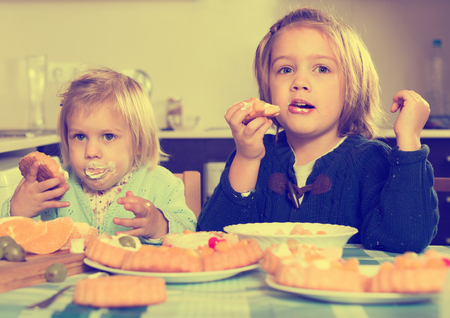 Two little girls with cream desserts at home kitchenの写真素材