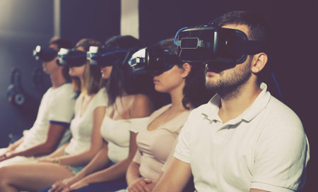 Young girls and guys wearing virtual reality headset playing video games together indoors