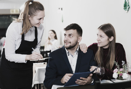 Couple is giving order to female waiter in luxury restaurante indoor.の写真素材