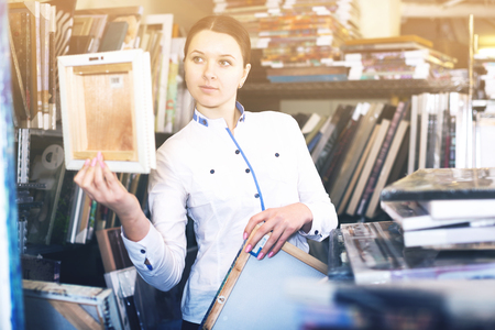 Positive woman is buying pictures in the furniture store.の写真素材