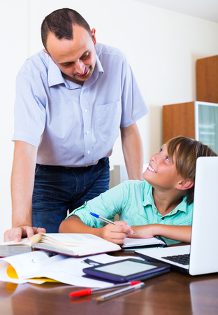 Smiling teenager having private lesson with school teacher in living roomの写真素材