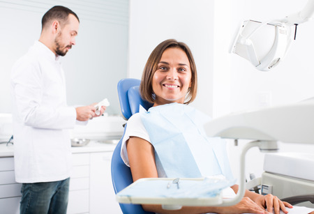 Young female is sitting satisfied in chair after treatment in dental officeの写真素材