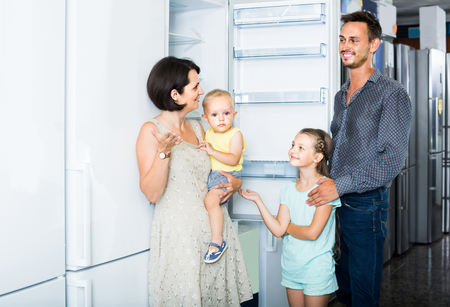 positive american family of four shopping new refrigerator in home appliance store の写真素材
