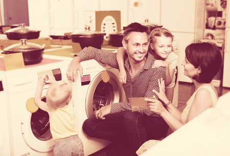 Smiling family with kids shopping modern washer in household retail sectionの写真素材