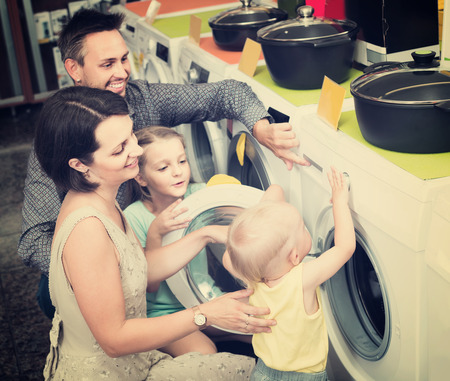 russian parents with two kids choosing washing machine in home appliance storeの写真素材