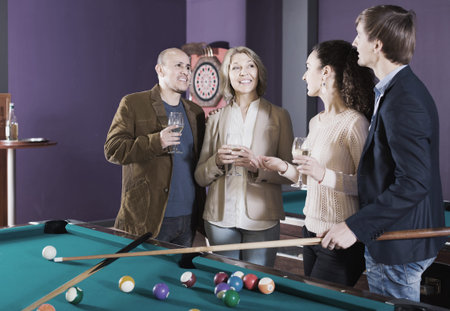 happy american mature and young couples hanging out in billiard club together