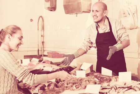 Friendly seller helping female customer to choose chilled fish の写真素材