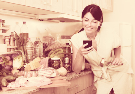 Female is searching new recipe in smartphone on the kitchen in home.の写真素材