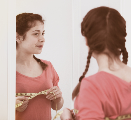 Young girl feeling successful with breast size gain at homeの写真素材