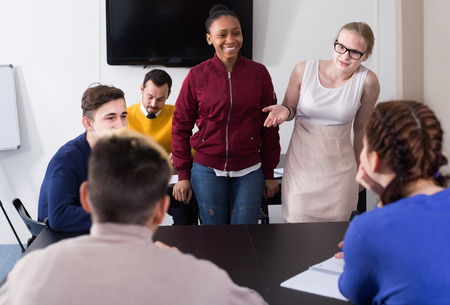 classmates having animated talks at break between classes sits by the tableの写真素材
