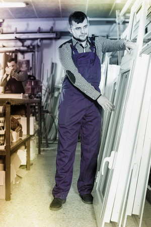 smiling professional labours with finished PVC profiles and windows at factoryの写真素材