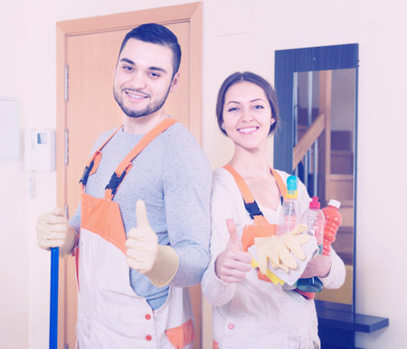 Portrait of smiling professional cleaners with equipment at door of client houseの写真素材