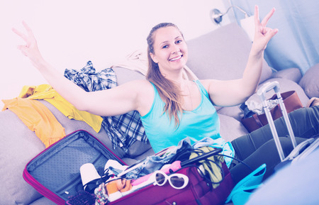 Smiling young female ready to depart for holiday indoorsの写真素材