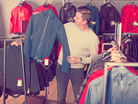 Glad man chooses clothes in a sports shopの写真素材