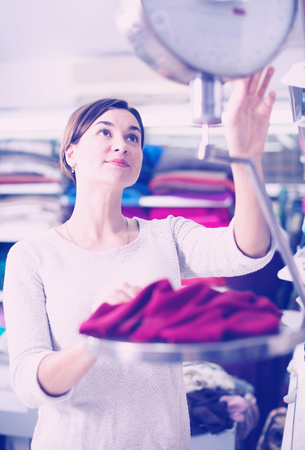 Young woman seller checking fabric weight on scales at drapery shopの写真素材