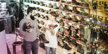 Glad couple deciding on new sneakers in sports equipment store. Focus on the manの写真素材