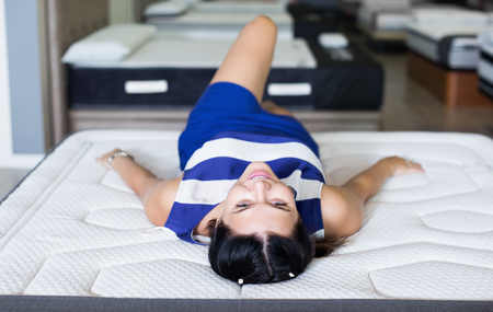 Young female is lying on mattress for relaxing in the furniture storeの写真素材