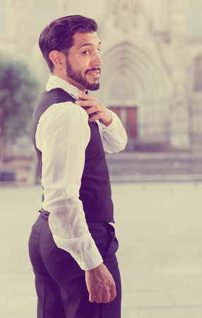 Bearded man shaking off something from his shoulder over cathedral backgroundの写真素材