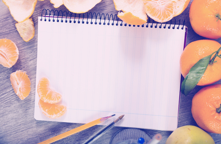 Notebook in range with writing utensils surrounded by fruitの写真素材